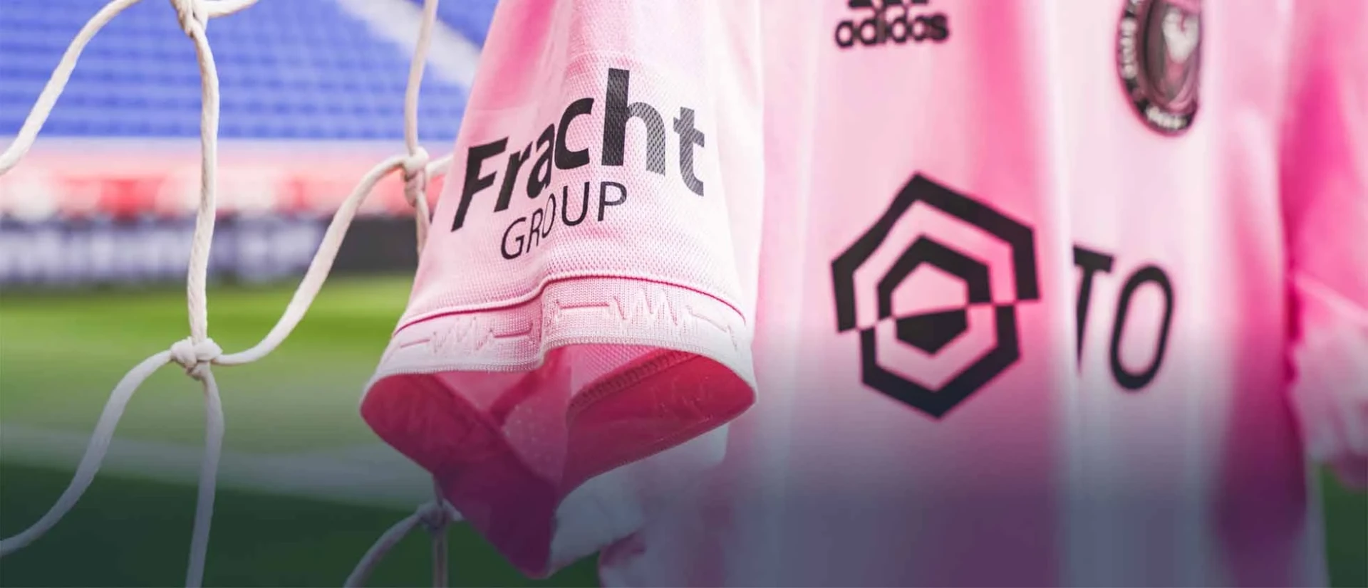 Close up view of an Inter Miami FC kit hanging on the goal netting with the Fracht Group logo shown prominently on the sleeve.