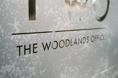 A close-up view of the words “The Woodlands” on a glass wall inside Adcetera’s office in The Woodlands, Texas.