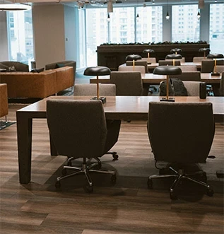 View across large office overlooking three rows of long reading tables with banker’s lamps to wall of windows, showing high-rise buildings across the street from Adcetera’s Chicago office, a Digital Marketing Agency.